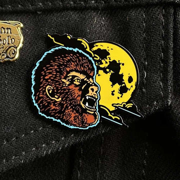 Pin with a wolfman head and moon design on a black background